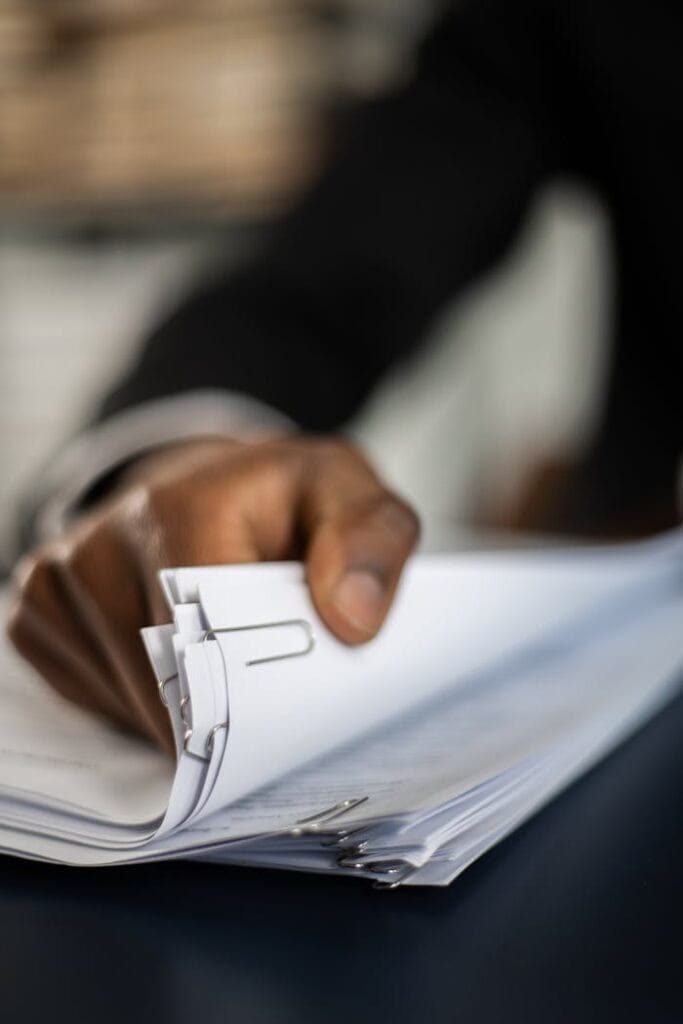 Close-up of hand organizing documents with paper clips, business focus.
